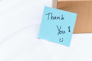 Thank you note on package home office business communication indoor setting close-up perspective gratitude concept photo