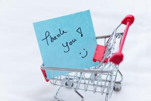Business thank you note in shopping cart retail setting gift idea minimalist design close-up view customer appreciation concept photo