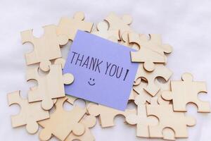 Thank you note on puzzle pieces business appreciation event office space creative environment close-up view connection concept photo