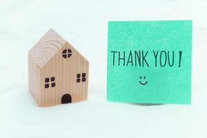 Thank you note next to wooden house model home office emotional content minimalist setting close-up view business appreciation photo