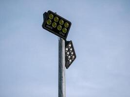 Illuminated floodlight fixtures pole outdoor setting industrial lighting daytime view urban concept photo