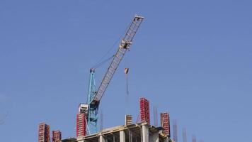 A large crane lifts materials at a construction site, showcasing the assembly of a new building with clear skies in the background video