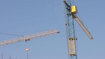 Crane machinery works diligently at a construction site, lifting heavy materials under a clear sky to build a new structure video