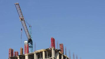 Construction activity features a crane lifting materials at a building site with cranes and machinery operating against a bright sky video
