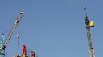 Multiple cranes are actively lifting heavy materials at a construction site, showcasing the bustling progress of the new building project video