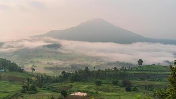 A view of a valley with green hills and a mountain in the distance video
