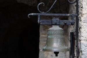 Rustic Bronze Bell Mounted on Weathered Stone Wall in Historical Setting photo