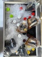 Bottles of soda and juice chilling on ice with colorful caps and plastic bags filled with beverages, creating refreshing display for party or gathering. ice keeps drinks cold and ready to serve photo