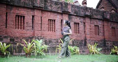 Handheld low angle view shot, Happy young woman is enjoying a quiet stroll, taking in the view and taking photos at an ancient site, Enjoy holiday travel. video