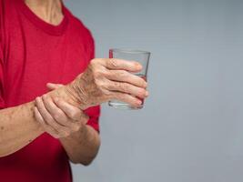 Close-up of hands trying to hold a glass of water. photo