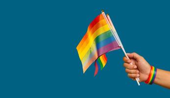 Close-up of a rainbow flags showing in hand against a blue background. photo