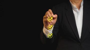 Businessman holding a pen and checking a mark on the boxes symbol is one of three options while standing on a black background. Space for text. photo