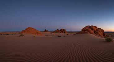 Picturesque desert scenery featuring rippled sand dunes and unique rock formations under a twilight sky photo