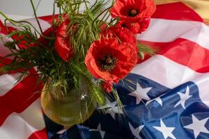 Brilliant red poppies dance on a vase against the bold tapestry of the American flag, echoing Memorial Days somber nostalgia photo