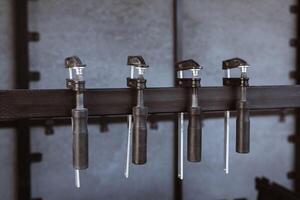 Four black clamps hang on a metal stand against a background of a slate wall on the construction site, prepared for fixing materials photo
