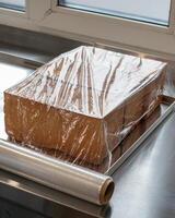 Golden loaf of bread under mysterious cling wrap, resembling modern art sculpture, perfect for World Baking Day celebrations photo