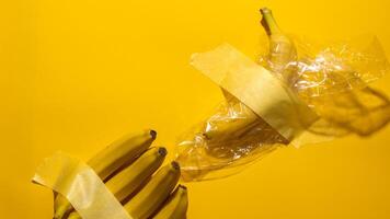 Bananas taped and plastic wrapped against a vivid yellow canvas, echoing Modern Art Days surreal fruit symbolism and quirky creativity photo