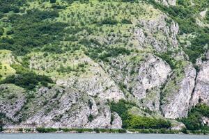 Rocky emerald hills cascade into serene waters, ideal for Earth Day reflections or Walpurgis Night nature reverie photo