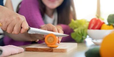 Chopping Fresh Vegetables. Close-up of a woman slicing a carrot while another woman observes. photo