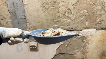 Gloved hand holding a dustpan of rubble whispers tales of abandoned restoration, echoing National Demolition Day and Pisanki traditions photo