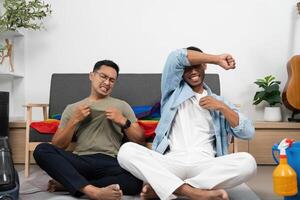 LGBTQIA Friendship and Joy. Two young men enjoying a fun moment while cleaning at home. photo
