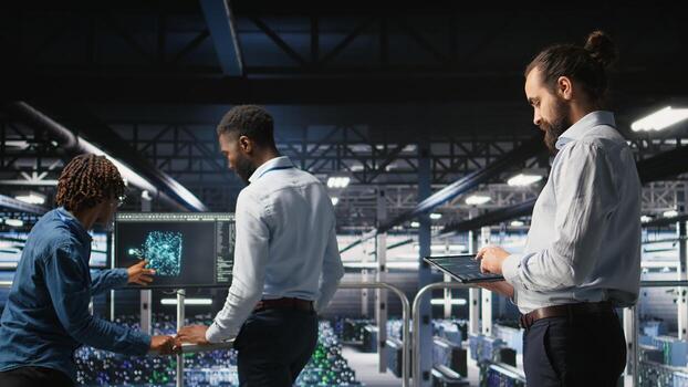 Programmers on data center industrial platform checking code on tablet, doing software updates. Server farm IT professionals cooperating, finetuning rackmounts configurations, photo