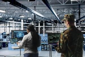 Military units in server room flagging unusual movement using machine learning detection tools. Team of army specialist in data center mapping airborne activity using predictive AI software photo