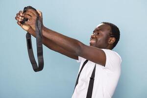 African american male photographer captures a personal moment, taking a picture of himself with his camera. His casual outfit and expressive pose create a compelling and engaging portrait. photo