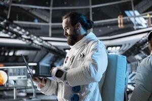 Astronaut researcher verifying navigation coordinates using laptop, carrying out research. Scientist wearing cosmonaut gear in spaceship monitoring life support systems during flight photo