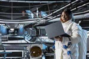 Astronaut using laptop to confirm suit integrity, monitoring life support systems. Orbital station crew member testing gear during routine equipment check using notebook, conducting safety checks photo