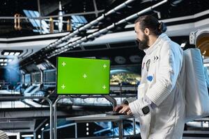 Astronaut in starship using green screen monitor to confirm suit integrity. Orbital station crew member testing gear during routine equipment check using chroma key mockup display photo