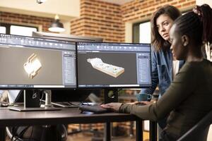 Black and caucasian female engineers collaborating at desk, trying to develop the geometry of 3d design for a construction company. African american developer using cad software on a multi monitor. photo