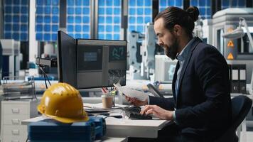 Male industry expert examining production data in a solar tech plant, ensuring innovation and efficiency to drive alternative energy success. Sustainable solutions for development. Camera B. photo