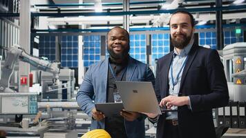 Team of diverse analysts consultants reviewing data and checklists in a high tech solar panel plant, ensuring manufacturing process meets sustainable energy and innovation standards. Camera A. photo