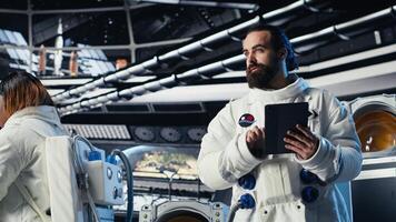 Astronaut reading mission plan on tablet before stepping out for scheduled operations outside space station. Cosmonaut checks analytics on device, preparing to leave after landing on planet photo