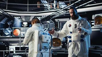 Astronaut waves hand, communicating with command center during videocall to share recent orbit discoveries. Cosmonaut salutes Earth team, provides scientific findings from spacecraft photo