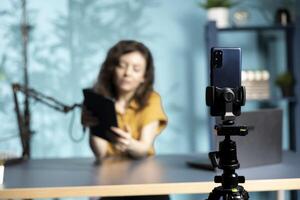 Focus on smartphone used by tech vlogger to present tablet to interested viewers. Close up of mobile phone used by woman reviewing digital device for technology enthusiasts photo