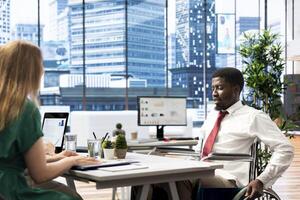 HR worker implementing diversity and inclusivity recruitment strategy for company, hiring person with paraplegia. Recruiter reaching agreement with african american wheelchair user photo