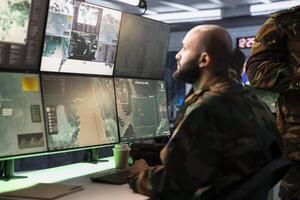 Military agent working in control room, analyzing aerial reconnaissance data to come up with warfare winning tactics. Intelligence corps agent controlling drones attacking strategic targets photo