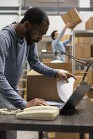Black warehouse staff handling efficient distribution and local delivery in industrial storage room, managing packages and order processing systems for a local brand. Small business. photo