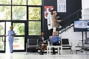 Different people sitting in the clinic waiting area for a checkup exam or discussion with a healthcare expert, young or elderly patients waiting in the lobby for a medical specialist. Health check. photo