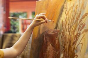 Skilled painter stands before a canvas painting a watercolor rustic artwork. Artist showing her skill and brush technique as she mixes dyes, creating a multicolored masterpiece. Close up. photo