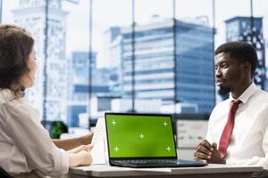HR worker implementing diversity recruitment strategy for company, using green screen laptop. Recruiter reaching agreement with african american man, using mockup notebook photo