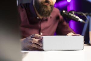Close up shot of packaged product ready to be unboxed by tech guru for for technology vlog. Focus on box presented by influencer urging fans to buy sponsoring partner merchandise photo