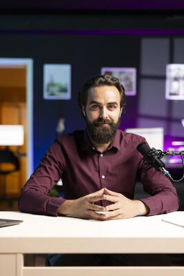Portrait of influencer in home studio using professional microphone to record live broadcast for online streaming platforms, talking with fans. Smiling media star hosts q and a session with viewers