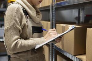 Industrial warehouse scene with employee counting merchandise to dispatch parcels. Shelving units filled with cargo highlight efficient logistics, delivery and inventory control operations. photo