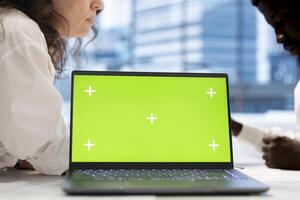 HR coworkers using green screen laptop to do preemployment assessments and background checks to potential job applicants. Headhunters use chroma key notebook to attract qualified candidates photo