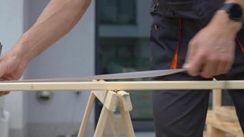 Man measuring wooden board during carpentry work in front of residential building. Concept of craftsmanship, woodwork and renovation work video