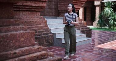 Handheld shot, Happy woman in casual clothes walking exploring and enjoying taking photos at an ancient site, Enjoy holiday travel. video
