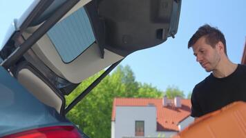Man loading suitcases into car trunk on sunny day. Concept of preparing for summer travel, vacation or road trip with luggage video